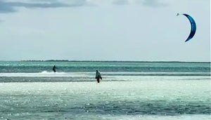 Person kite surfing on a body of water with a clear sky. Cayo Guillermo